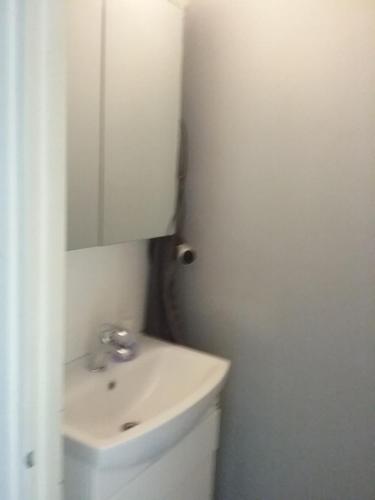 Baño blanco con lavabo y espejo en Hamina Poitsila, 