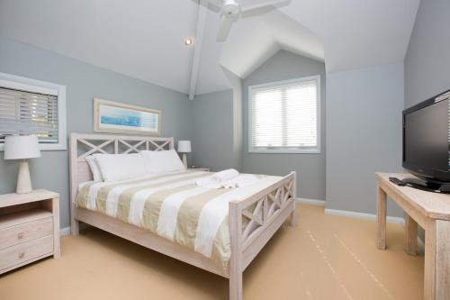 a bedroom with a bed and a flat screen tv at Blueys Retreat in Blueys Beach