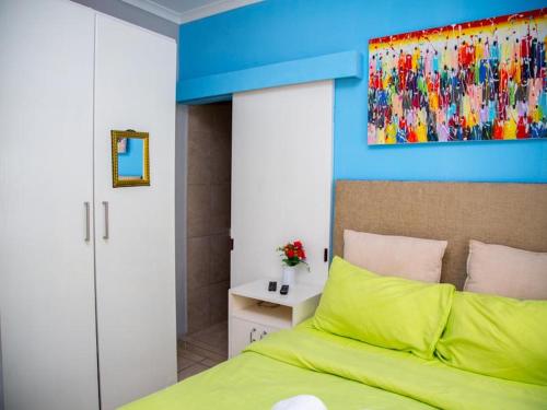 Un dormitorio con una cama verde y una pared azul en Annex Lodge @ Ndabeni en Ciudad del Cabo