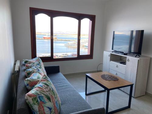 uma sala de estar com um sofá, uma televisão e uma mesa em Mirando al Sur em Ushuaia
