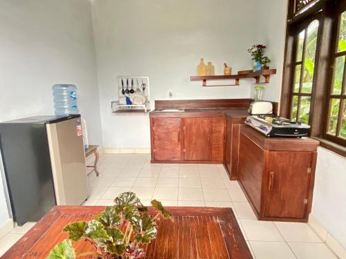 a kitchen with wooden cabinets and a table with a plant at Twin Inn in Ubud