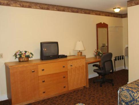 a hotel room with a television on a dresser with a desk at Stardust Motel in North Stonington