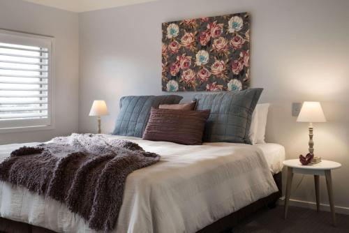 a bedroom with a bed with a floral painting on the wall at Courthouse Orchid Villa 6 in Daylesford