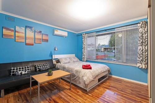 1 dormitorio con paredes azules, 1 cama y 1 mesa en Ocean Views Apartment 2 min walk to train & ocean, en Halletts Cove