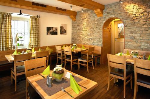 a restaurant with wooden tables and chairs and a brick wall at Gasthof Gigl in Neustadt an der Donau