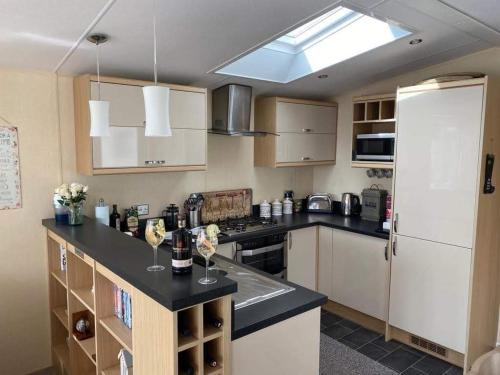 Il comprend une cuisine équipée d'un comptoir noir et d'un réfrigérateur. dans l'établissement Rockley Park, Arne View, à Hamworthy