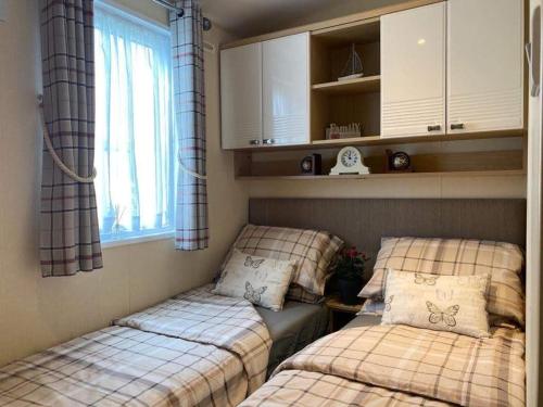two beds in a small room with a window at Rockley Park, Arne View in Hamworthy