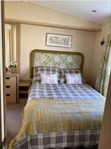 a bedroom with a bed with a plaid blanket and pillows at Rockley Park, Arne View in Hamworthy