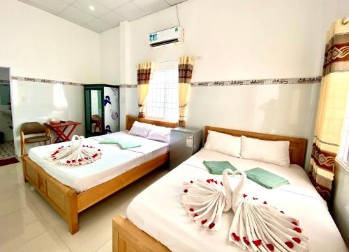 Dos camas en una habitación de hotel con rosas. en Song Ngoc Guesthouse, en Phu Quoc