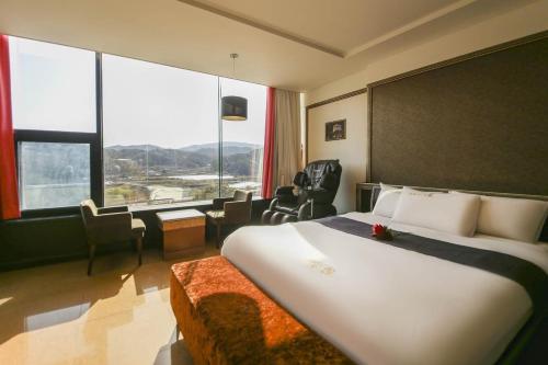 a hotel room with a bed and a large window at Ambassador Hotel in Suncheon