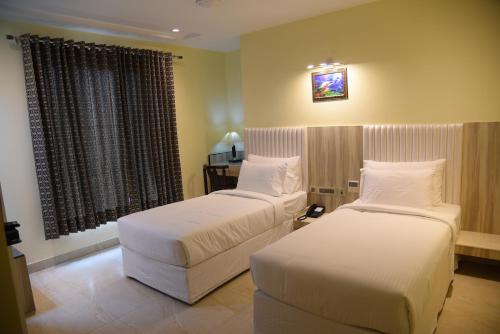 a hotel room with two beds and a window at Broadway Inn in Jaipur