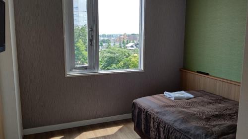 um quarto com uma cama e uma grande janela em Tabist Tsukuba Sky Hotel em Tsukuba