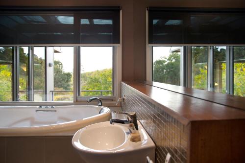 a bathroom with a sink and a tub and windows at Daylesford Spa Villa 4 in Daylesford
