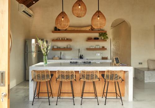 a kitchen with a large white island with three bar stools at Villa Cerah in Uluwatu