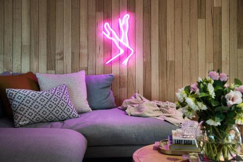 a purple couch with a pink neon sign on a wall at Dollywood in Daylesford
