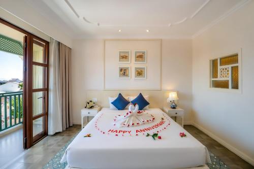 a bedroom with a happy anniversary cake on a bed at Lantana Riverside Hoi An Boutique Hotel & Spa in Hoi An