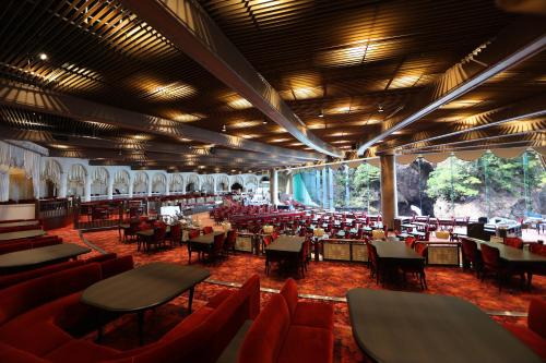 a restaurant with red chairs and tables in a building at Hotel New Akao in Atami