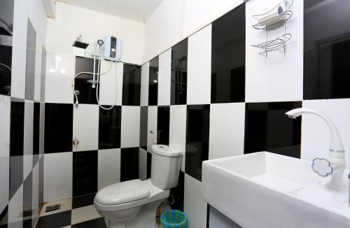 a black and white bathroom with a toilet and a sink at Citrus Cafe & Restaurant in Kandy