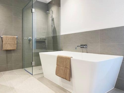 La salle de bains est pourvue d'une baignoire et d'une douche en verre. dans l'établissement WSP Lux 3B2B Apa Southern Cross Station, à Melbourne