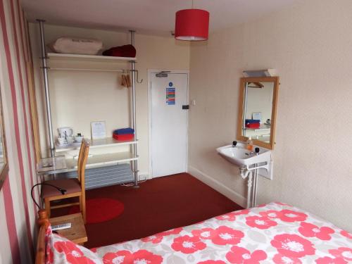 a small room with a bed and a sink at Angel Guesthouse in Tiverton