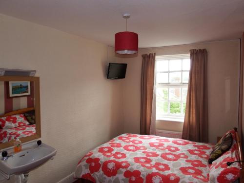 a bedroom with a bed and a sink and a window at Angel Guesthouse in Tiverton