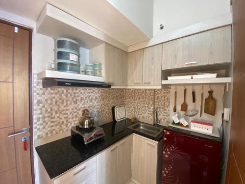 a kitchen with wooden cabinets and a black counter top at Comfy 2 Bedroom Apartmen Pavilion Permata Surabaya in Dukuhpakis