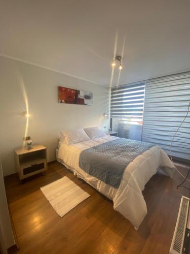 1 dormitorio con 1 cama y 1 mesa con lámpara en Monterosso Apart, en Concepción