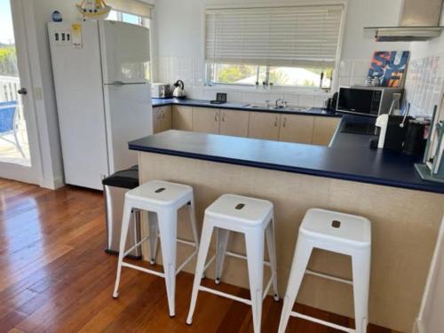 a kitchen with two stools and a counter with a refrigerator at Sinclair Surfside Stay in Surf Beach