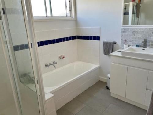 a white bathroom with a tub and a sink at Sinclair Surfside Stay in Surf Beach