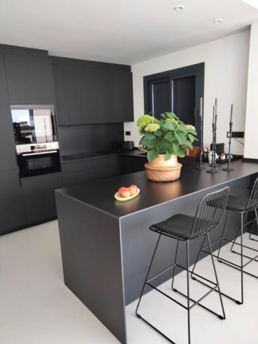 a kitchen with a black island with chairs and a plant at Faro 3 in Torredembarra