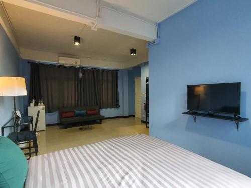 HOUSEMODE - BAANYAI @ Wongwian Yai في بانكوك: غرفة نوم بسرير وتلفزيون بشاشة مسطحة