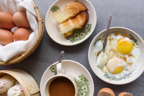 - une table avec des assiettes d'œufs, du pain grillé et une tasse de café dans l'établissement Himalaya Villa's, à Murree