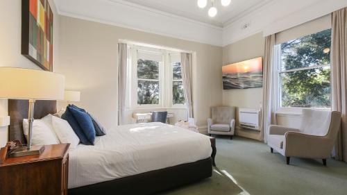 Un dormitorio con una cama y una silla y ventanas. en The Riversleigh, en Bairnsdale