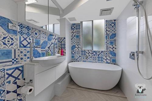 baño azul y blanco con bañera y lavamanos en KozyGuru / Clovelly / 2B Kozy APT / NCL037 en Sídney