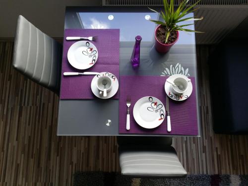 a table with white plates and a plant on it at Apartamenty Słupsk in Słupsk
