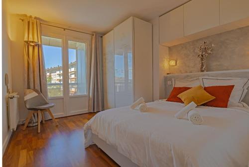 1 dormitorio con 1 cama blanca grande y ventana grande en L'échappee du 36 - 4 chambres dans le Triangle d'Or à 100m du lac, parking gratuit, en Annecy