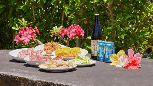 a table with plates of food and a bottle of wine at Pension Snadun in Ginoza
