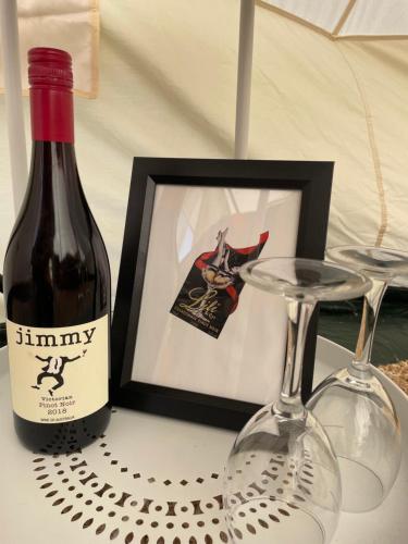 Una botella de vino y dos copas en una mesa. en Cosy Glamping Tent 1, en Ararat