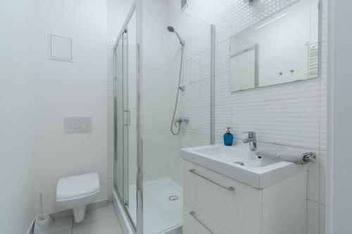 a white bathroom with a sink and a shower at Blue Apartment Browar Central in Poznań