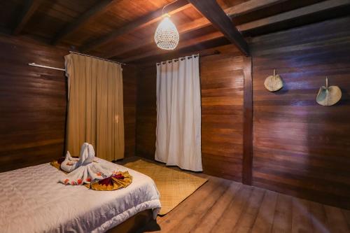 a bedroom with a bed in a room with wooden walls at Gili Ilalang Village in Gili Trawangan