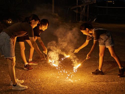 four girls are playing with sparklers on the street at Pension Snadun in Ginoza
