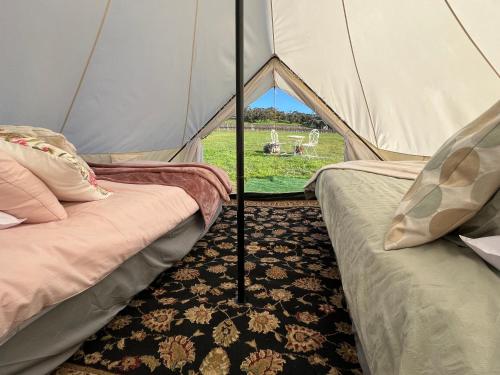 two beds in a tent with a view of a field at Cosy Glamping Tent 2 in Ararat