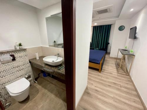 a bathroom with a sink and a toilet and a bed at AirReside Hotel Apartments Gold Crest in Lahore