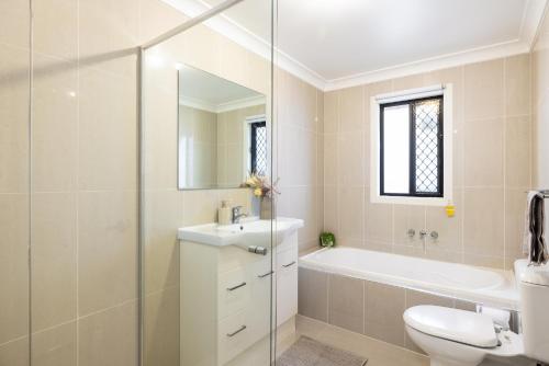a bathroom with a toilet and a sink and a tub at Great Location! Close to Restaurants & Train! in Brisbane