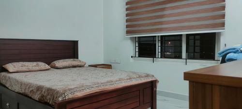a bedroom with a bed and two pillows on it at Luxurious Apartment with a pool and gym near Trivandrum railway station in Trivandrum