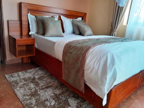 a bedroom with a large bed with a wooden headboard at Olina Hotel and Apartments Kampala in Kampala