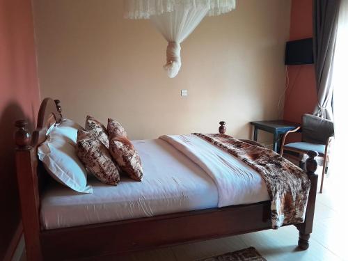a bed with pillows on it in a bedroom at Olina Hotel and Apartments Kampala in Kampala