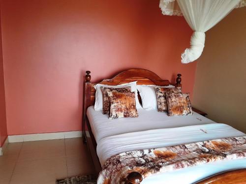 a bed in a bedroom with a red wall at Olina Hotel and Apartments Kampala in Kampala