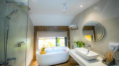 a bathroom with a tub and a sink and a mirror at Hoianan Boutique Hotel in Hoi An