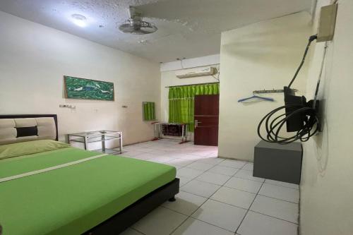 - une chambre avec un lit vert et une télévision dans l'établissement OYO 92818 Penginapan Garuda Syariah, 